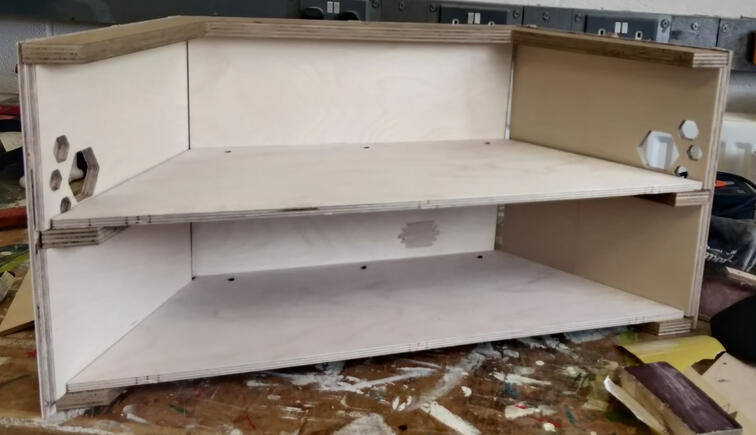 half hexagon wooden prototype with shelf and hexagonal holes at the edges
