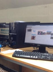 A desktop computer and keyboard on a desk, with square images arranged across the screen