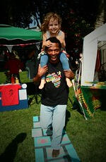 an adult with a child on his shoulders plays on the hopscotch